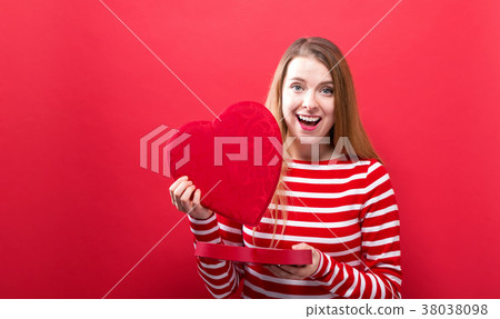Happy young woman holding a big heart gift box 38038098