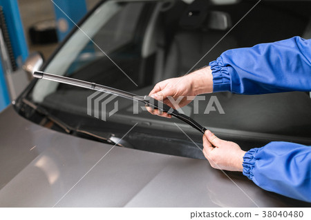 Technician is changing windscreen wipers on a car 38040480