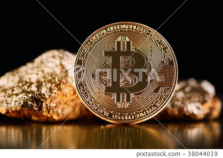 Golden bitcoin in front of gold lumps representing 38044019
