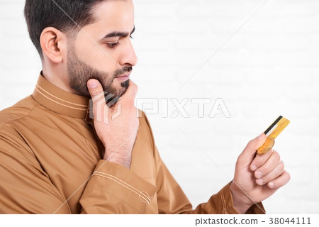 Arabian man keeps golden credit card in his hands. 38044111