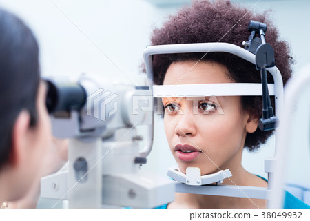Optician measuring women eyes with refractometer 38049932