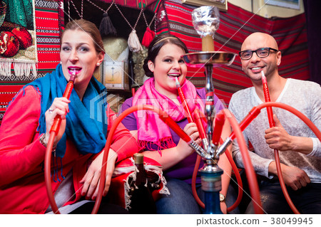 Friends smoking a hookah in shisha lounge 38049945