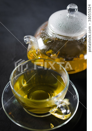 Cup of delicious herbal tea and glass teapot. Cup of delicious herbal tea and glass teapot. 38055824