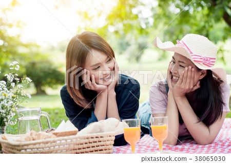 two asian girlfriends lying on the lawn, Women in park during th two asian girlfriends lying on the lawn, Women in park during th 38065030