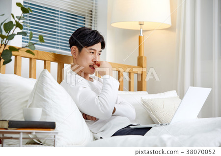 20 year old man working in bed on a leisure afternoon 38070052