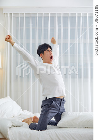 Twenties man stretching, stretching, stretching, stretching in bed 38071188