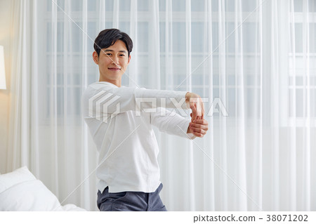 Twenties man stretching, stretching, stretching, stretching in bed 38071202