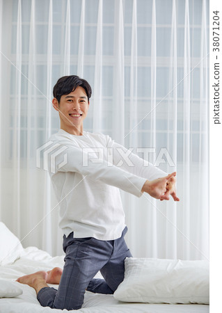 Twenties man stretching, stretching, stretching, stretching in bed 38071204