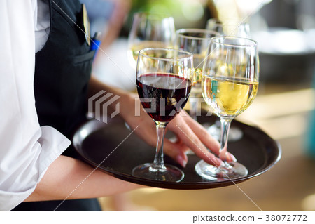 Waitress holding a dish of champagne and wine glasses at festive event 38072772