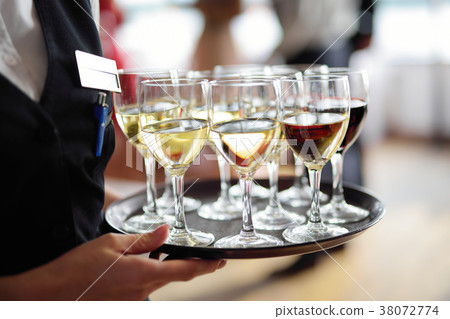 Waitress holding a dish of champagne and wine glasses at festive event 38072774
