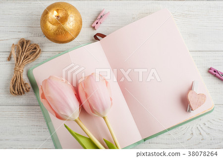Pink notebook, tulips and lit candle 38078264