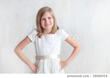 Portrait of pretty little girl in white dress with arms akimbo indoor 38080434