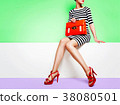 Fashion image of shoes and bags. Striped dress and bag with red shoes and orange 38080501