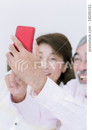 Bright senior age image Senior couple taking selfie with smartphone Focus on smartphone Bright senior age image Senior couple taking selfie with smartphone Focus on smartphone 38086261