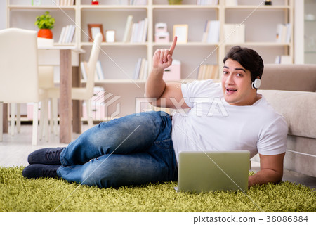 Man working on laptop at home on carpet floor Man working on laptop at home on carpet floor 38086884