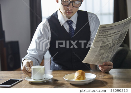Stylish businessman drinking coffee while reading English newspaper 38090213