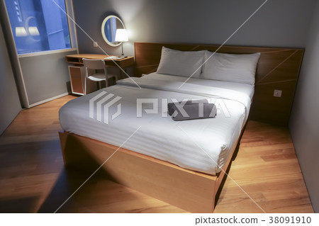 Bed in small simple hotel bedroom 38091910