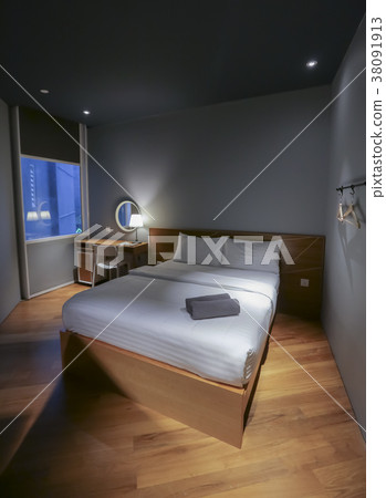 Bed in small simple hotel bedroom 38091913