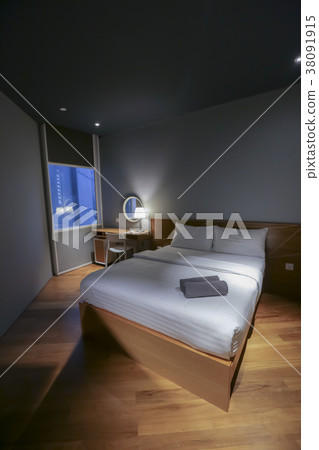 Bed in small simple hotel bedroom 38091915