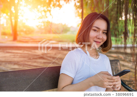 Asian Teen smile listening music from her Phone 38096691