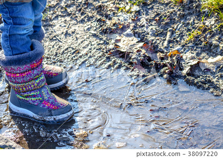 Child stands on icy dirty puddle Child stands on icy dirty puddle 38097220