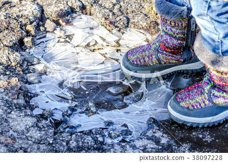 Child stands on icy dirty puddle 38097228