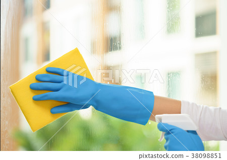 Housekeeper cleaning mirror with yellow cloth. 38098851