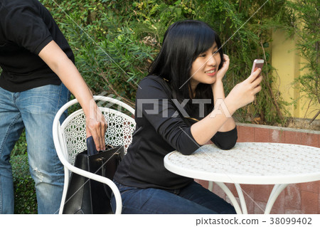 Thief trying to steal and walk away the shoulder bag while woman Thief trying to steal and walk away the shoulder bag while woman 38099402