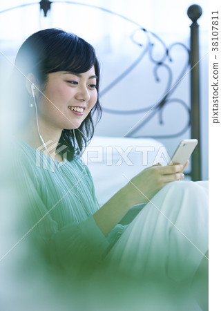 Woman listening to music with smartphone and earphones Woman listening to music with smartphone and earphones 38107811