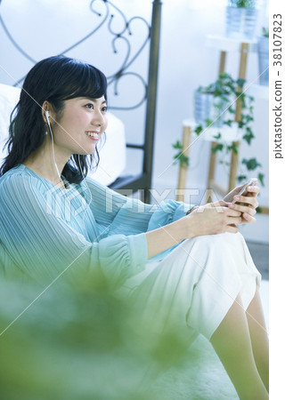 聽到與智能手機和耳機的音樂的婦女 聽到與智能手機和耳機的音樂的婦女 38107823