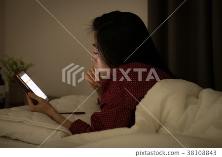 Young Japanese woman looking at smartphone in bed 38108843