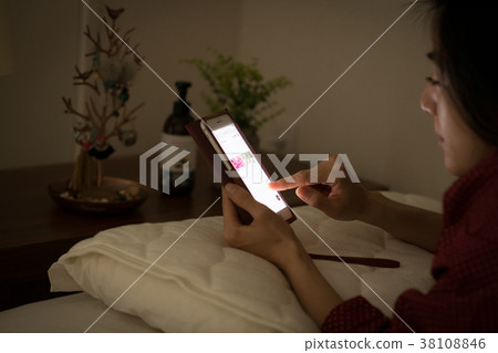Young Japanese woman looking at smartphone in bed Young Japanese woman looking at smartphone in bed 38108846