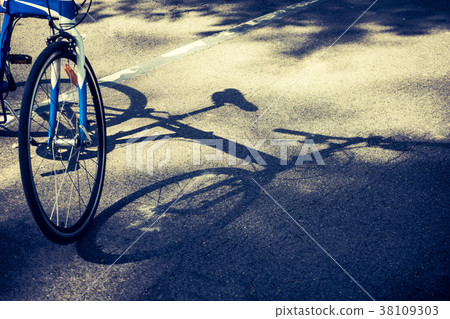 Bicycle wheel and shadow on bike lane in a park. 38109303