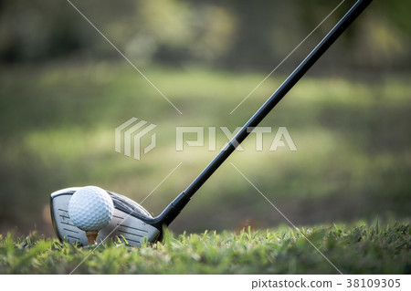 golf ball on a tee with golf club on the fairway. 38109305