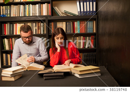 a man and a woman reading a book in the library 38119748