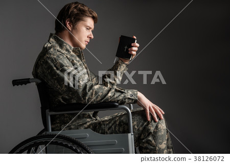 Cheerless disabled young man holding the Bible 38126072