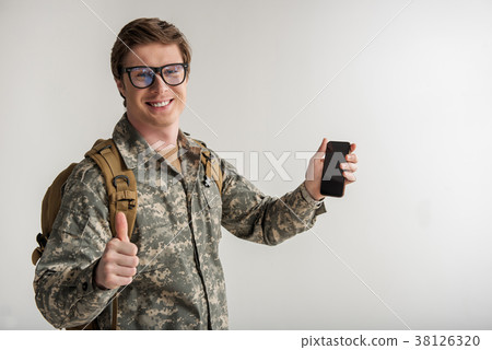 Cheerful military guy enjoying his cellphone Cheerful military guy enjoying his cellphone 38126320