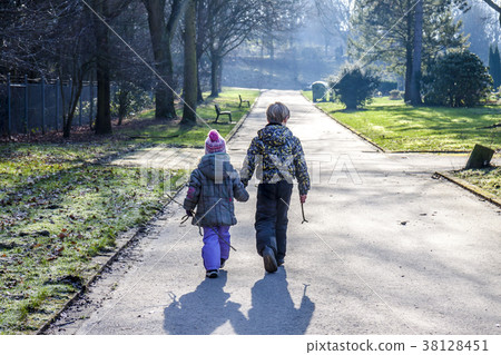 Little boy and girl holding hands and walking a Little boy and girl holding hands and walking a 38128451