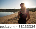 Girl stands on the beach against the sunset. 38133326