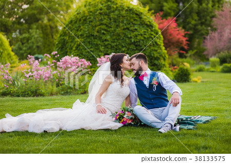 Beautiful married couple kissing on the grass 38133575