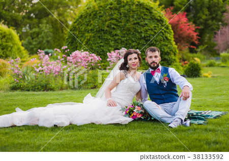 Beautiful married couple sitting on the grass in 38133592