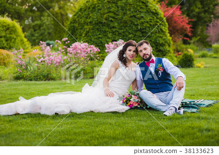 Beautiful married couple sitting on the grass 38133623