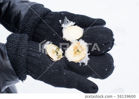 Gold coins bitcoin in mittens in winter. Crypto 38139600