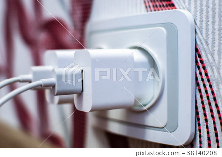 cell phone chargers plugged into the socket 38140208