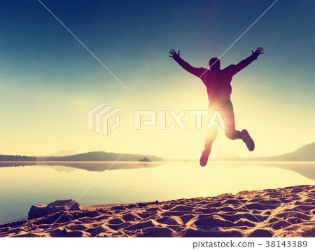 Adult crazy man jumps near water on against sun 38143389
