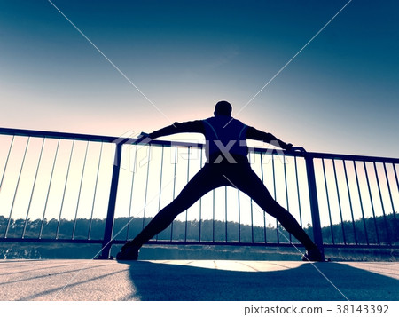 Runner body stretching on bridge path.Sun outlines 38143392