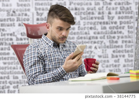 Young happy businessman smiling while reading his 38144775