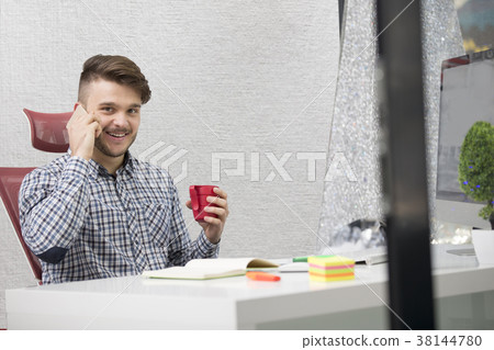 Young happy businessman smiling while reading his 38144780
