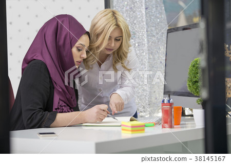 European woman and asian muslim woman working European woman and asian muslim woman working 38145167