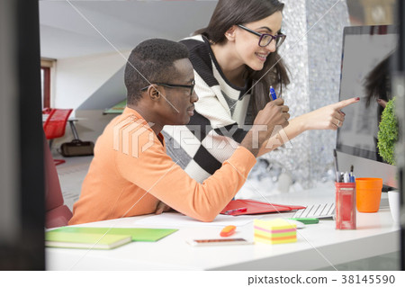 Two diverse work colleagues smiling and writing 38145590